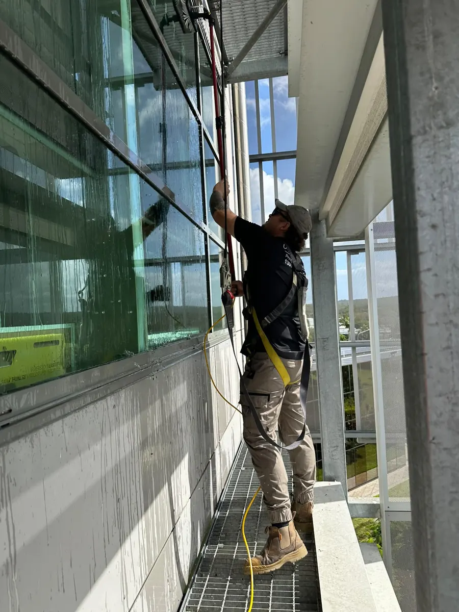 Clean Exteriors technician safely cleaning windows at height, Nerang